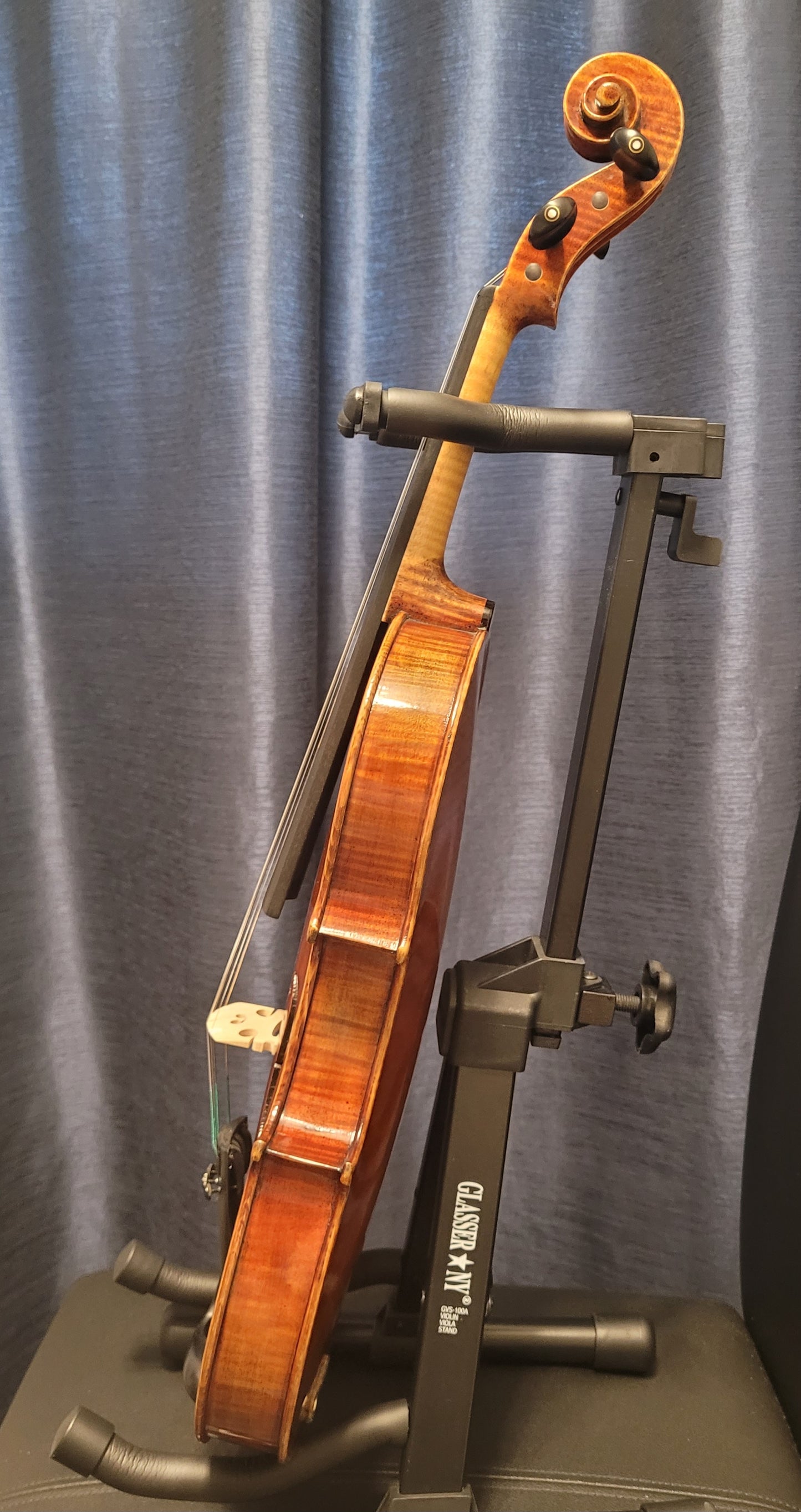Violin on a stand against a gray curtain background