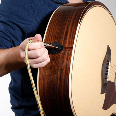 Person tuning a brown acoustic guitar with a white background