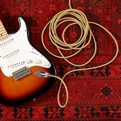 Electric guitar with coiled cable on a red patterned surface