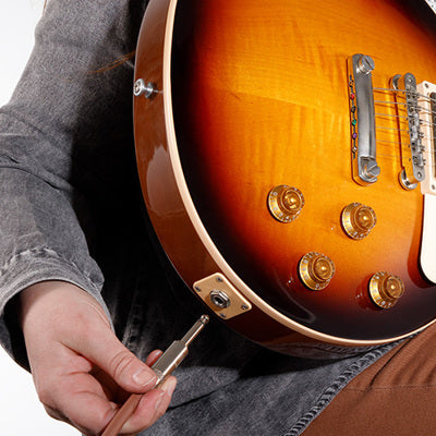 Person adjusting a guitar with a close-up of the guitar's body and neck.