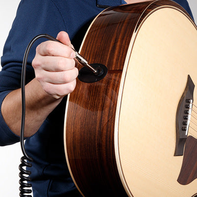 Person adjusting a string on a guitar with a close-up of the action and bridge.