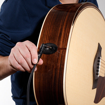 Person tuning a wooden acoustic guitar with a white background