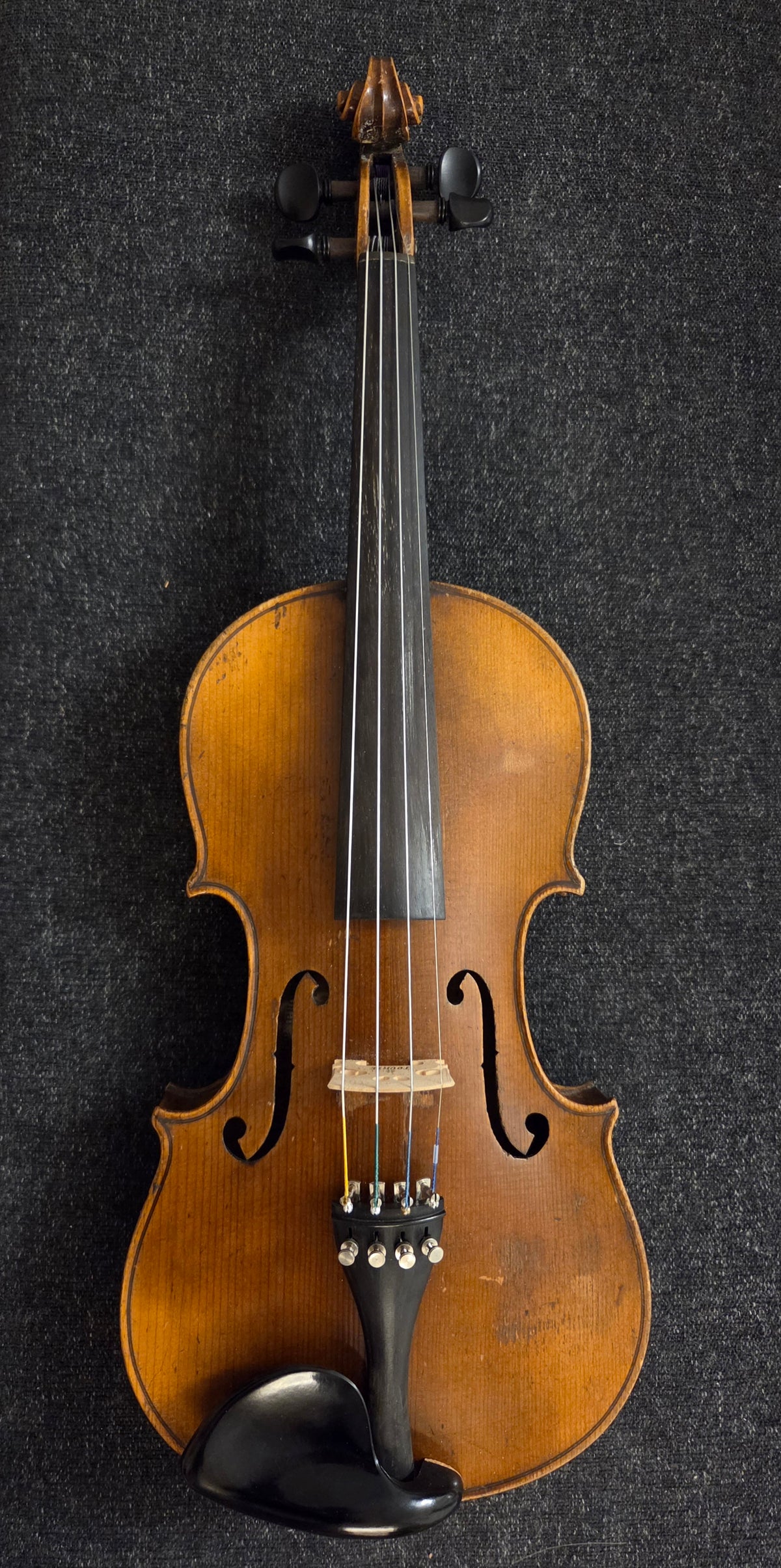 Front of antique violin on a grey background