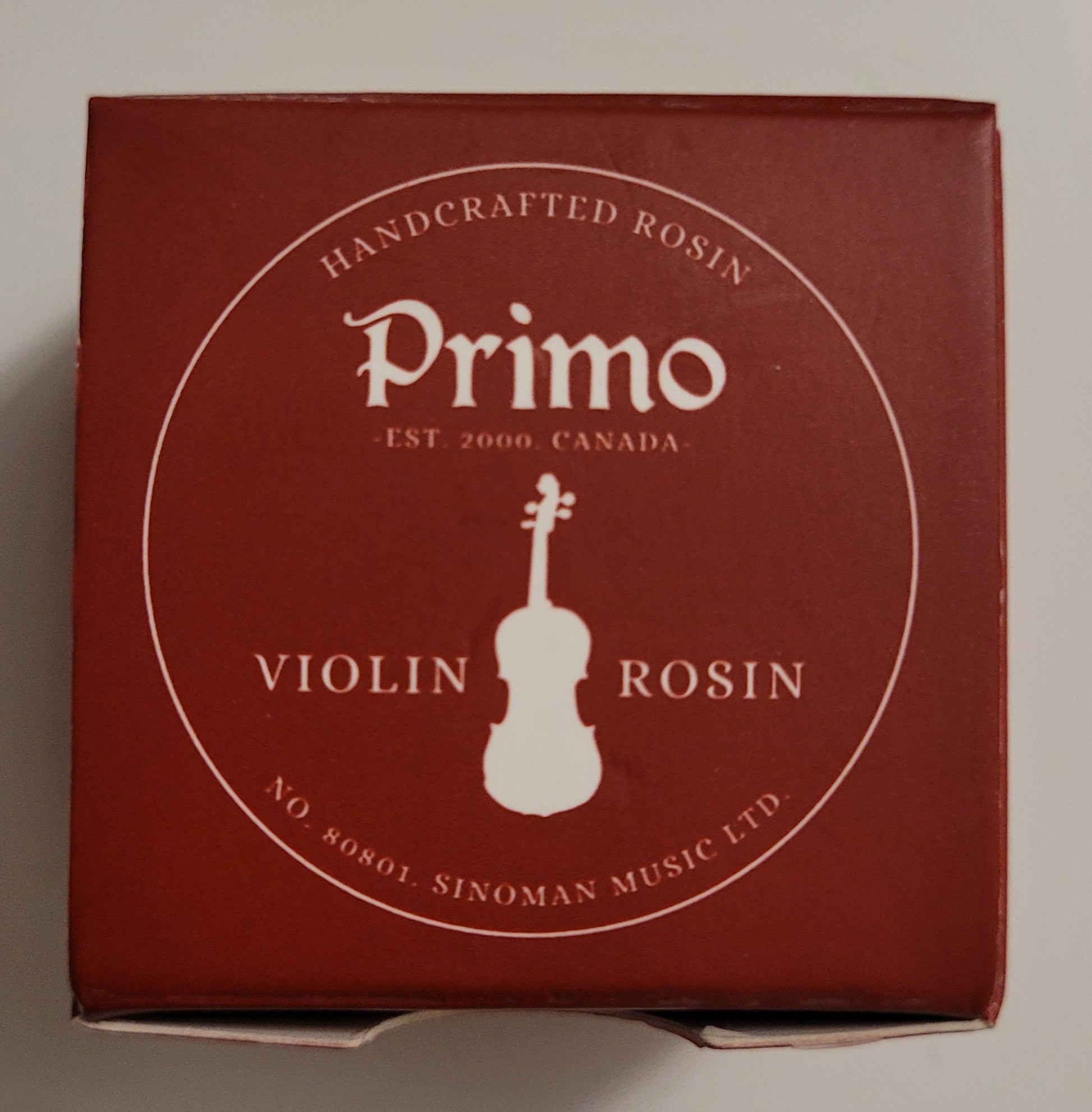 Box of Primo violin rosin with a red background and white text.